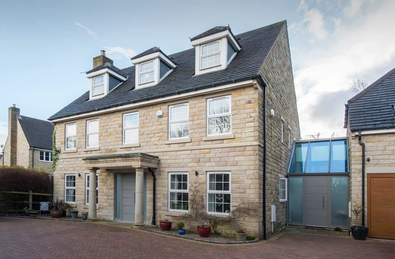 Luxury home featuring white windows and a clear grey front door with side panels