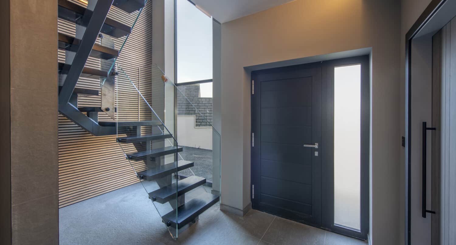 Modern hallway featuring an aluminium front door and a contemporary staircase