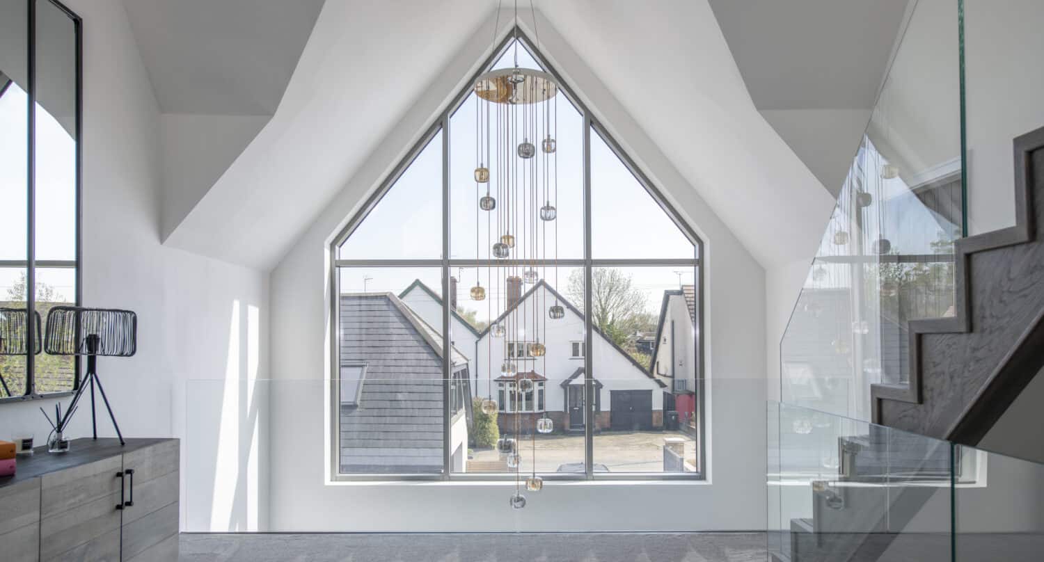 Luxury high ceiling landing featuring large pendant light and shaped aluminum windows