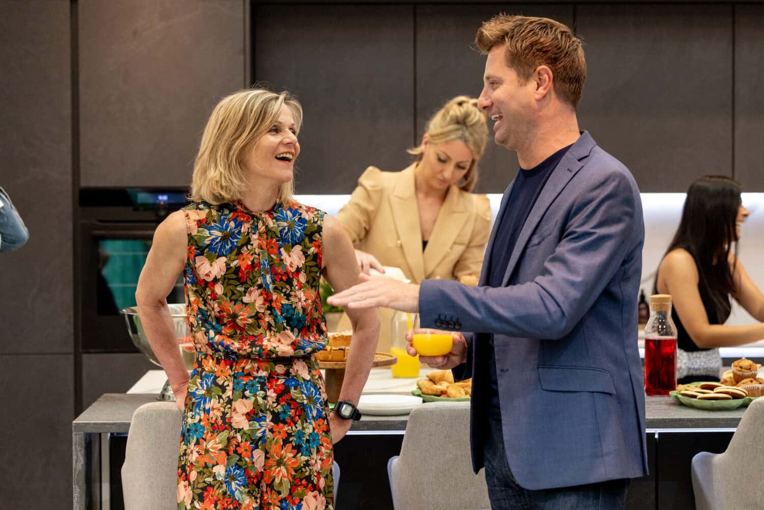 Two people having a conversation at a party in a modern kitchen