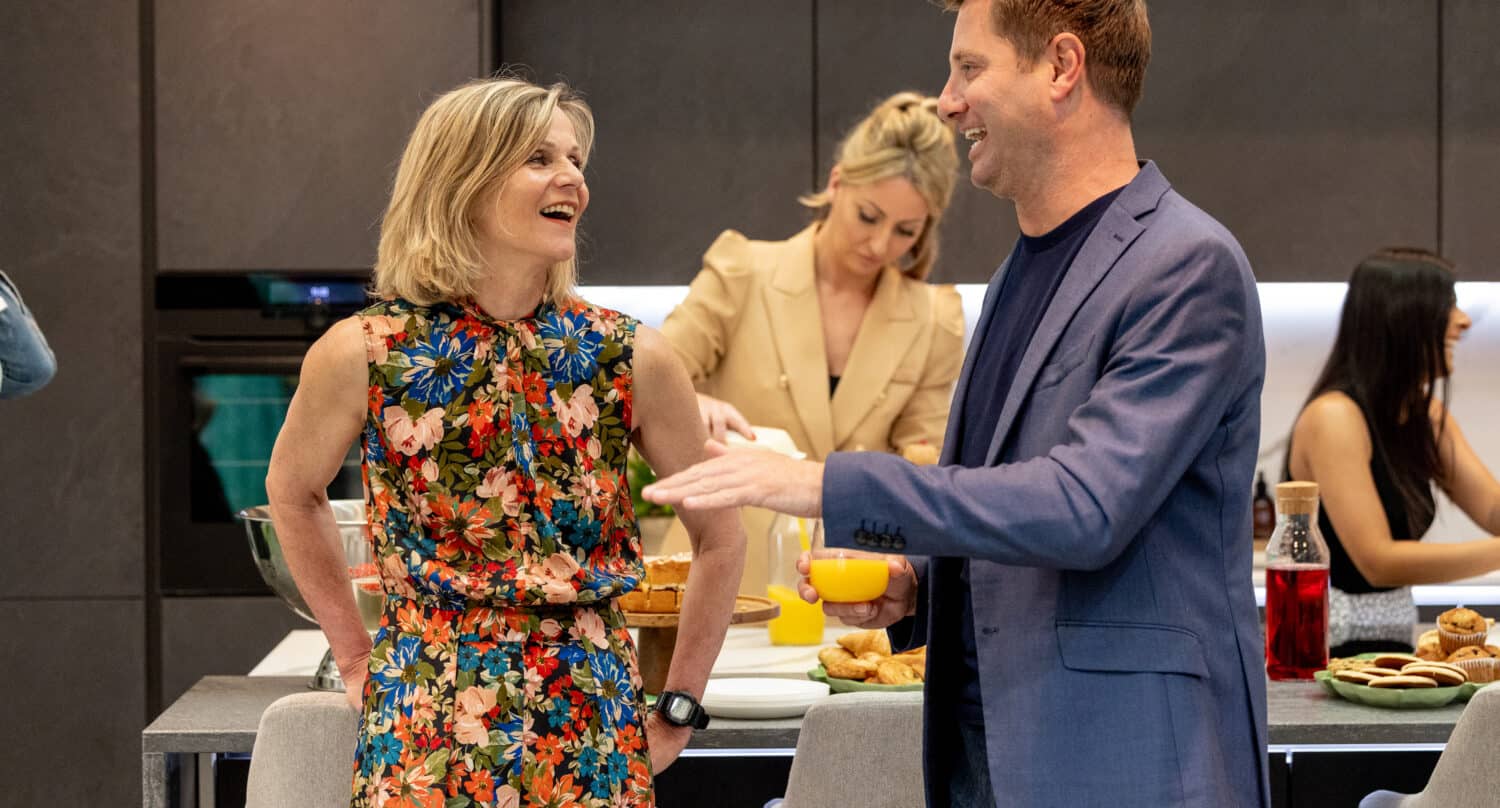 Two people having a conversation at a party in a modern kitchen