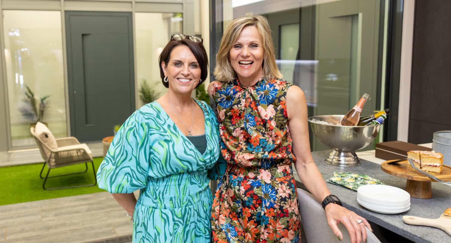 Two ladies posing in a modern kitchen at a party