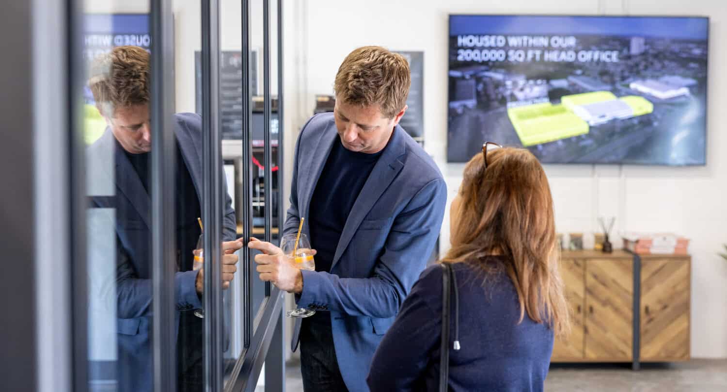 A man and a lady taking a close look to aluminium windows in a showroom