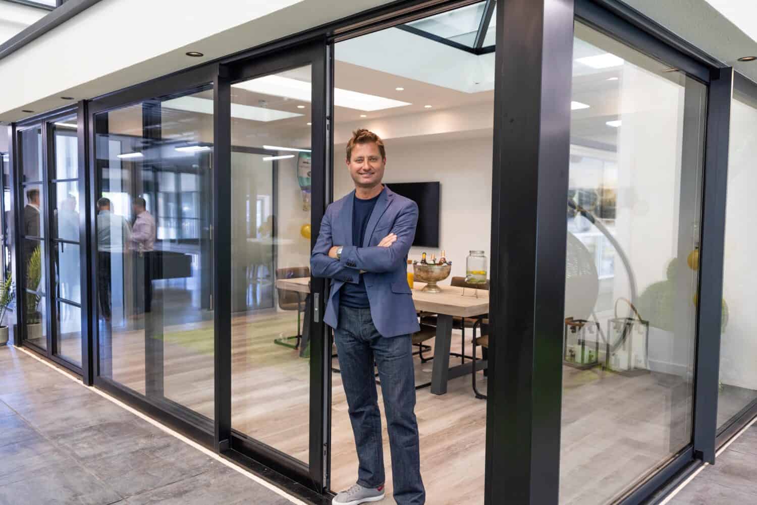 A man posing in a modern open plan extension featuring black sliding doors in a showroom