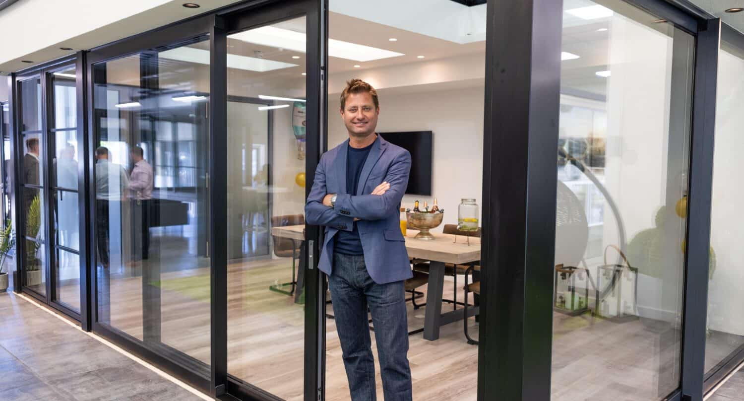 A man posing in a modern open plan extension featuring black sliding doors in a showroom