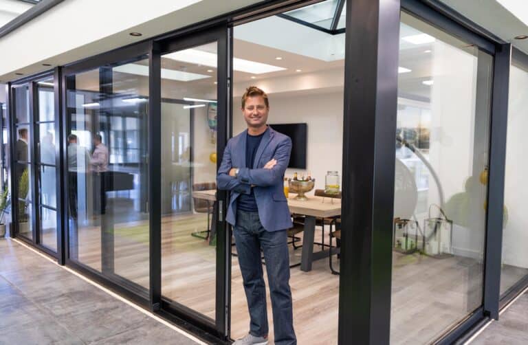 A man posing in a modern open plan extension featuring black sliding doors in a showroom
