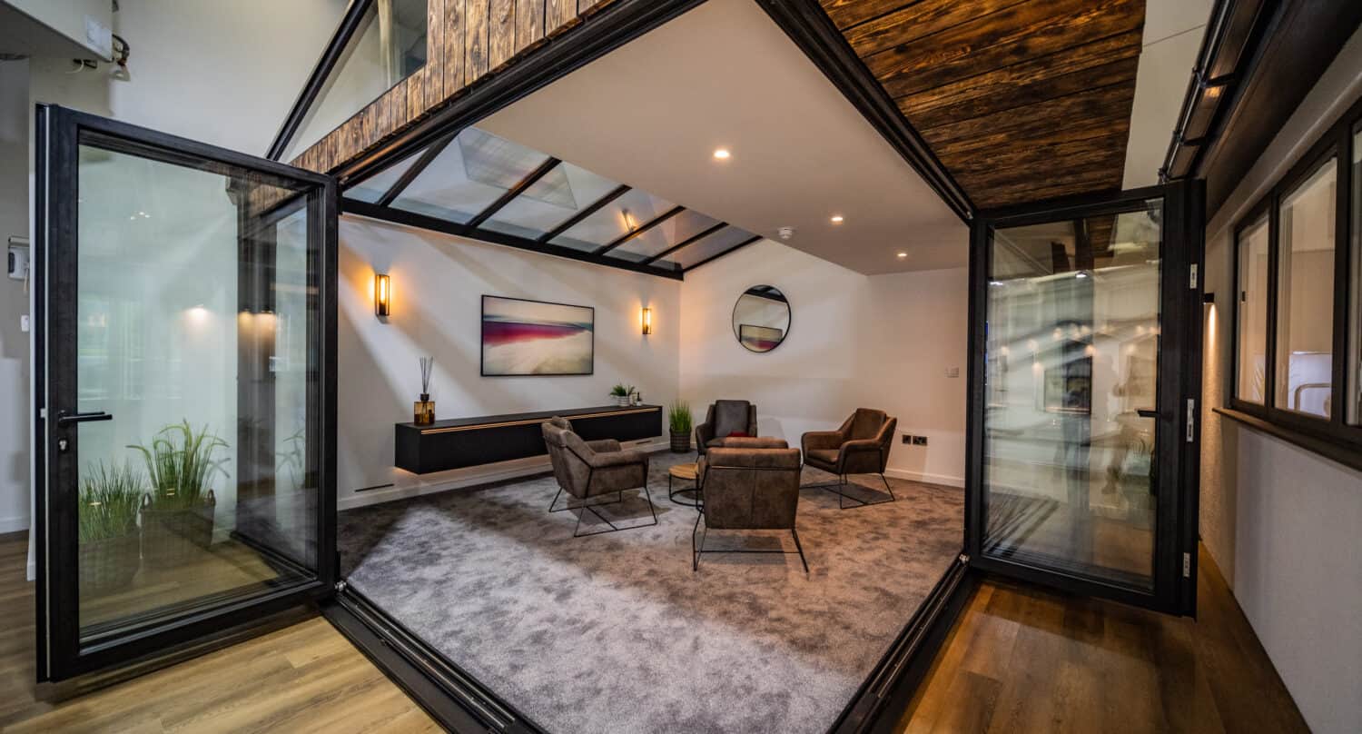 Modern aluminium bifolding doors opening to a modern living room space in a showroom