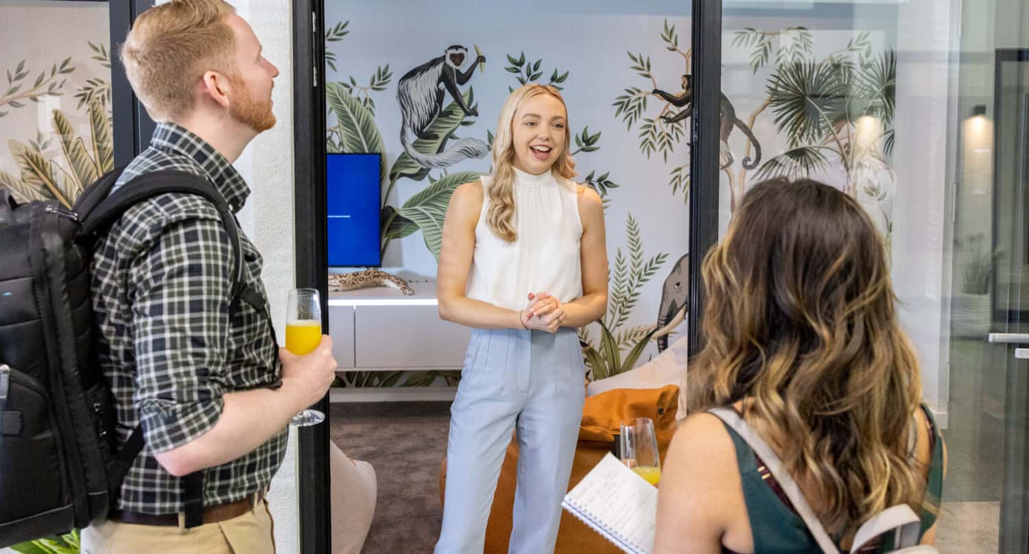 Three people talking in a modern living room space that's featuring bifold doors