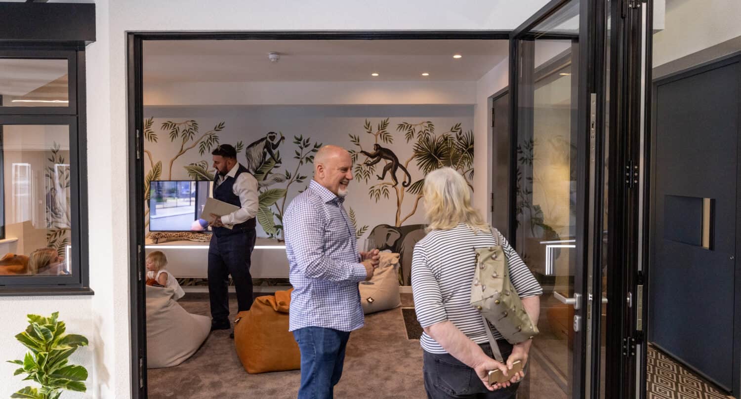 A few people having a conversation in a living room space that's featuring bifolding doors