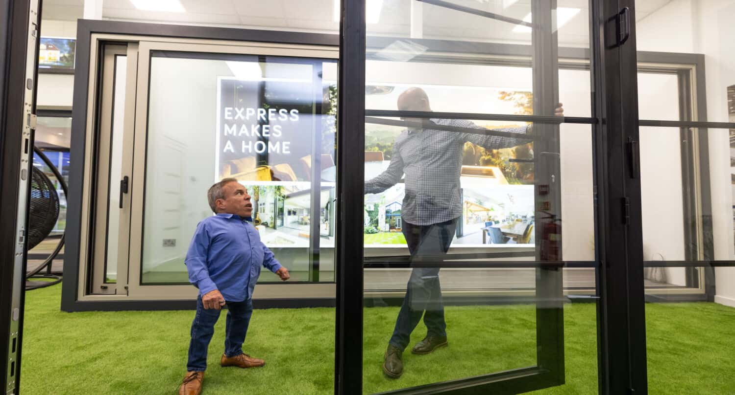 Two men having a conversation by aluminium bifold doors in a showroom