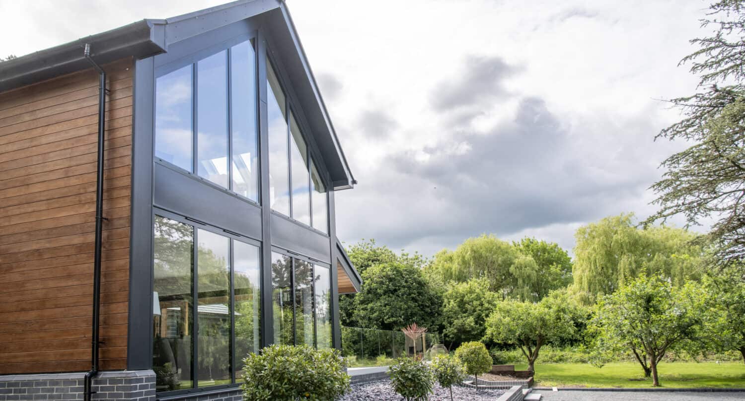 Side view of a house featuring glass curtain walling and a glass balustrade in the patio area