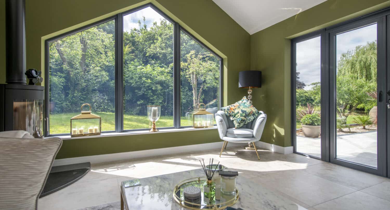 Modern living room space featuring a big aluminium shaped window facing the garden