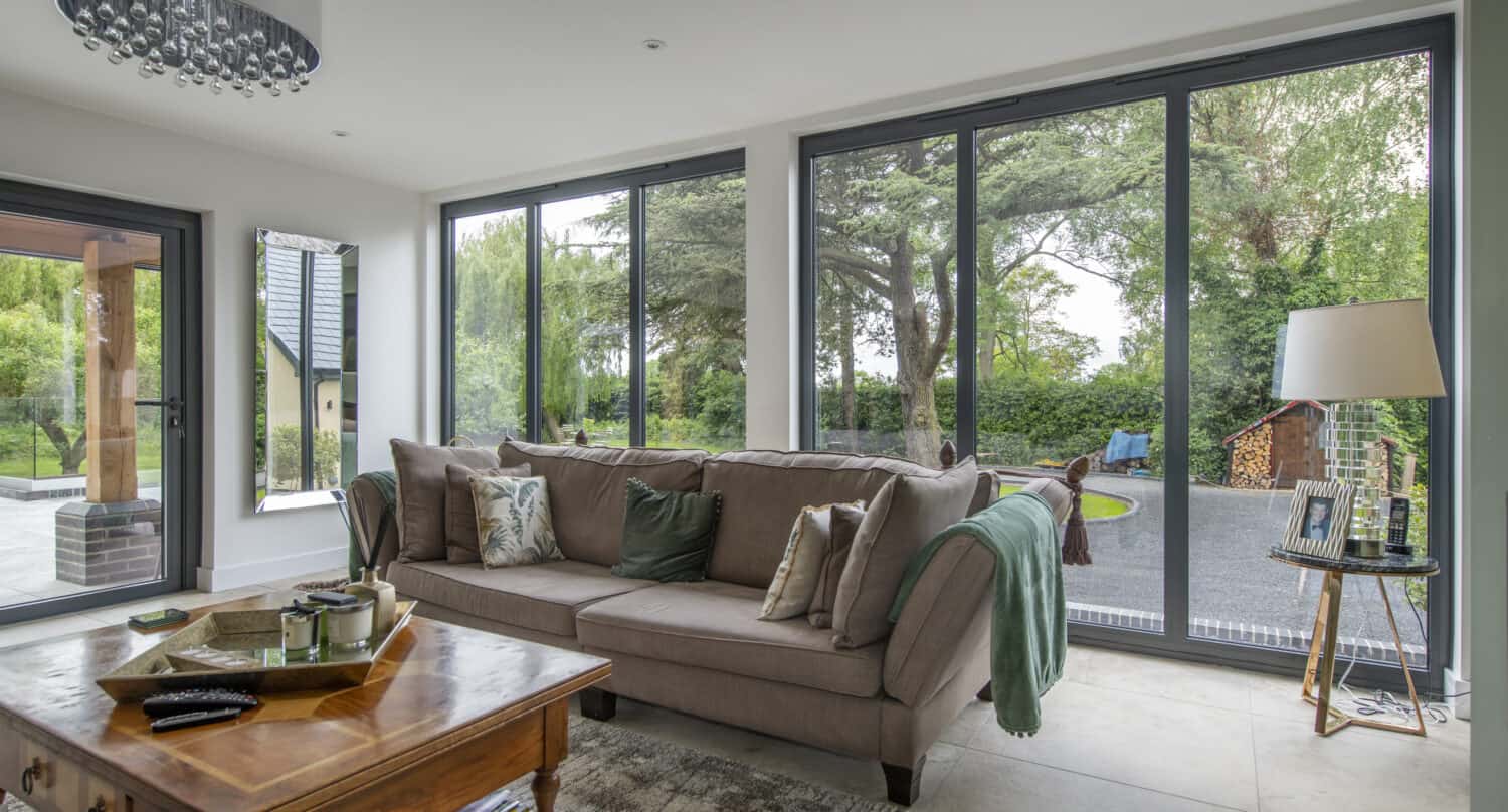Modern living room space featuring a brown sofa and two sets of three panel windows