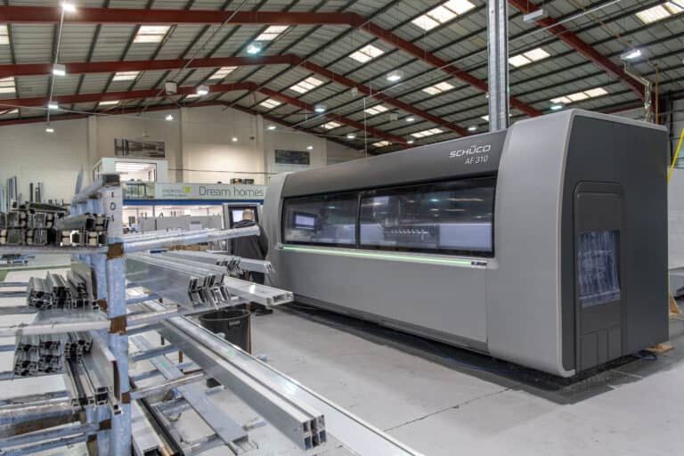 Man operating a machine in a bifold and sliding doors manufacturing warehouse