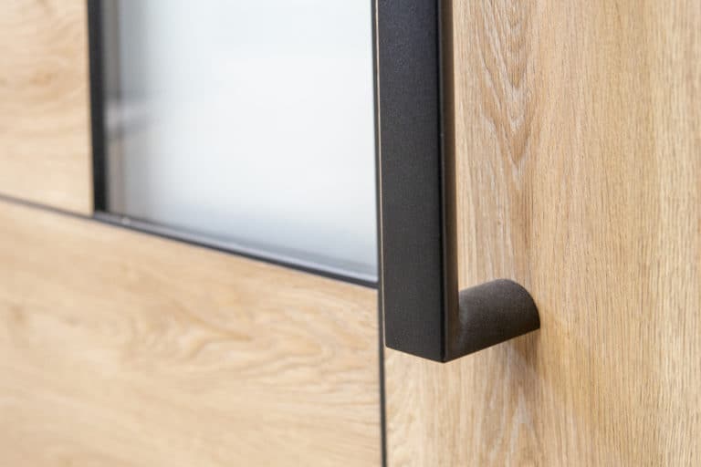 Close-up of a modern wooden front door with a frosted glass panel and a black metal handle.