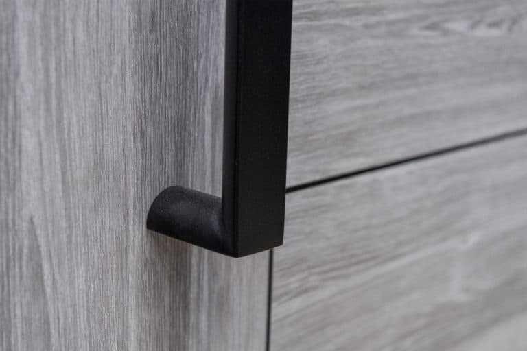 Close-up of a modern black metal handle on a light gray wooden cabinet or drawer, showing the wood grain texture and sleek design—perfect for coordinating with sliding doors in contemporary interiors.