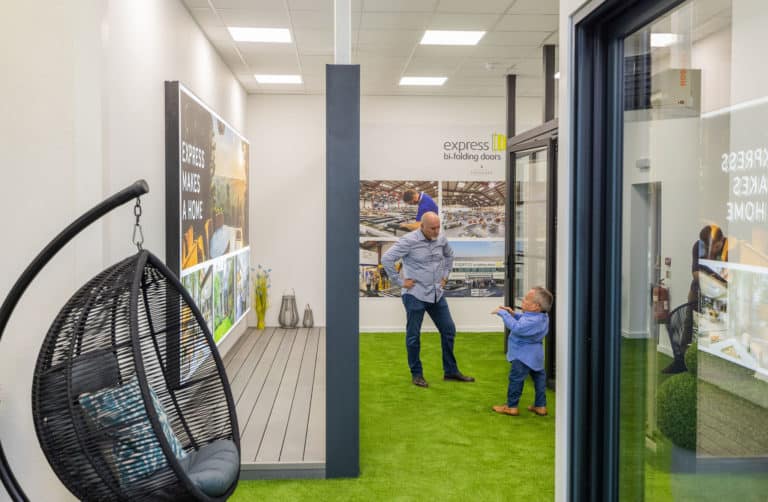 Two men having a conversation by aluminium bifold doors in a showroom