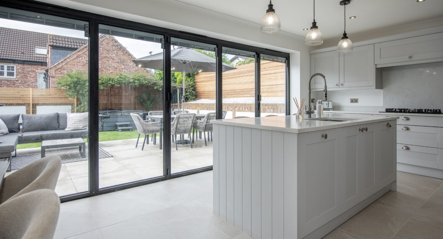Modern kitchen extension with black aluminium bifold doors and patio dining area