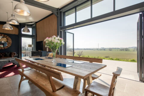 Aluminium bifold doors opening from dining room to countryside patio in modern open-plan home
